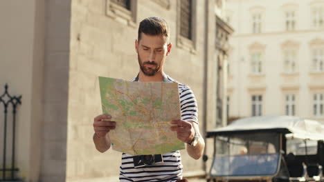 turista masculino perdido sosteniendo un mapa de la ciudad y buscando direcciones en la calle del casco antiguo