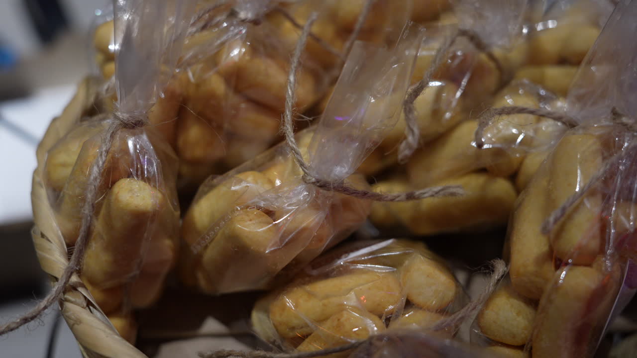 Detailed view of golden achiras bread wrapped in plastic, artistically arranged in a rustic basket. Warm lighting enhances texture and highlights the artisanal quality of these Colombian treats
