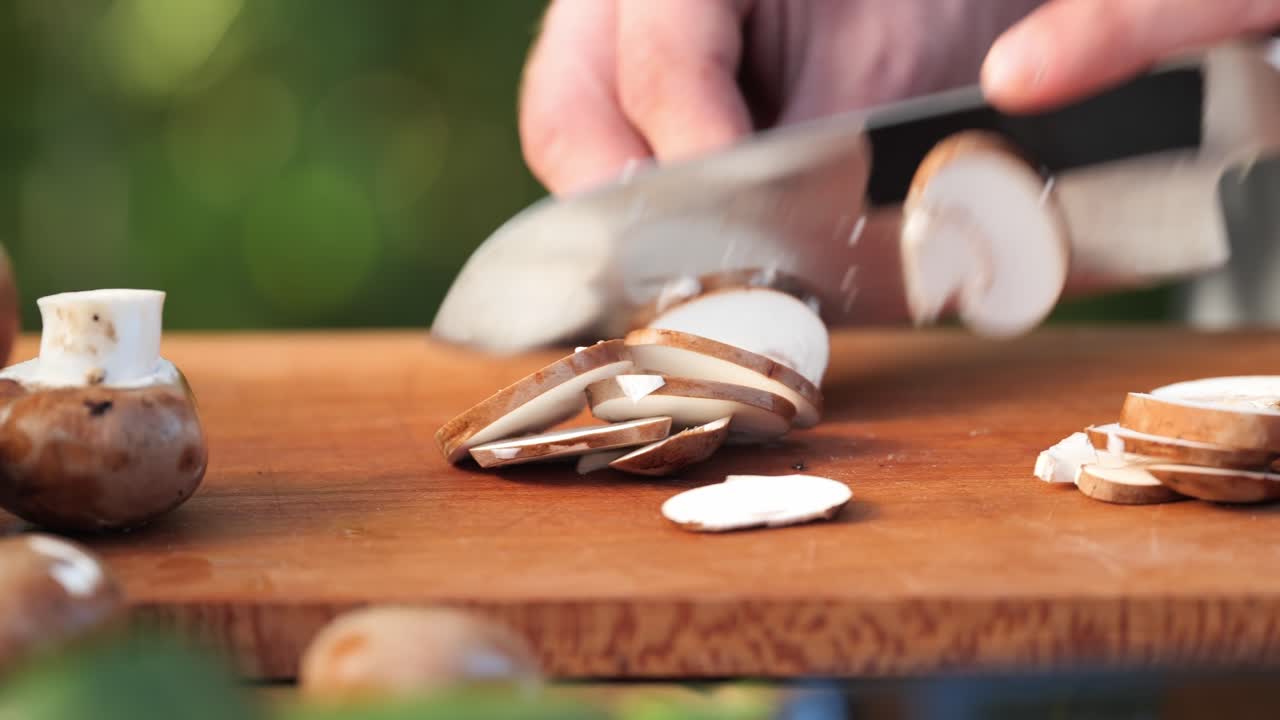 a young man cuts brown mushrooms on a wooden board close up