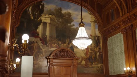 candelabro brillante cuelga del techo en una habitación de madera con una enorme pintura de pared