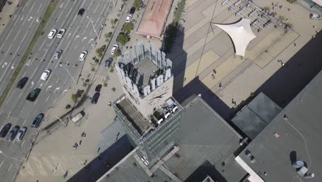 Cinematic-orbiting-of-the-Riga-Clock-tower-looking-down-in-Latvia,-Europe-tilt-up-in-the-end-of-the-shot-to-reveal-the-cityscape,-Drone