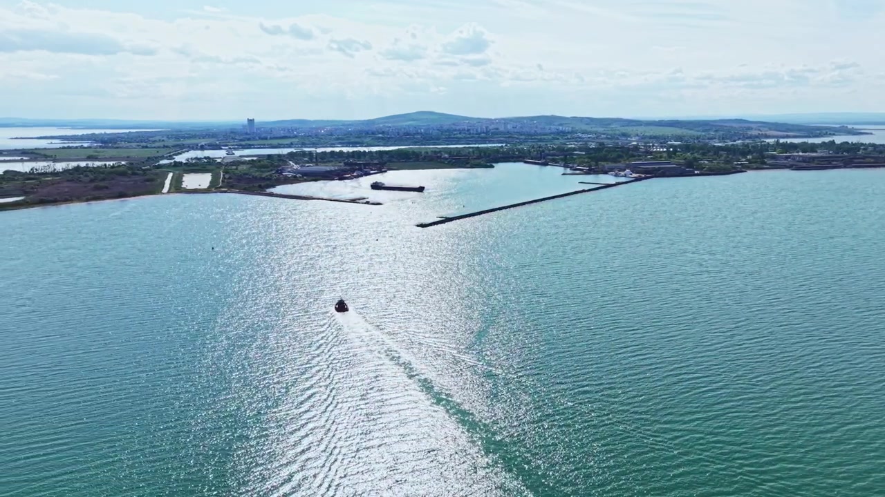 Luminoso panorama marittimo. Baia illuminata dal sole con acqua scintillante. Drone cattura baia scintillante e porto distante. Il filmato aereo mostra un mare tranquillo con lo skyline della città sullo sfondo