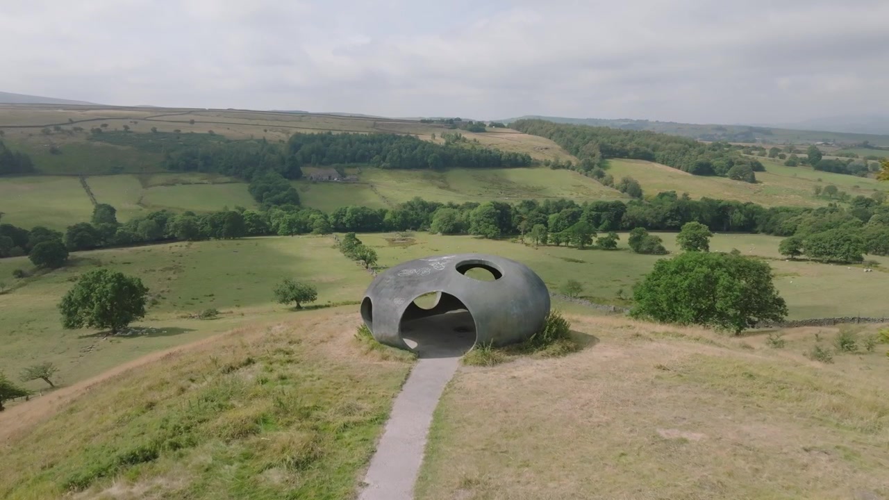 Das Atom Panopticon, Wycoller, Pendle, Lancashire, UK. Kunstwerk im Sonnenlicht mit langsamem Herannahen vorbei an Bäumen, das eine weite Landschaft offenbart.