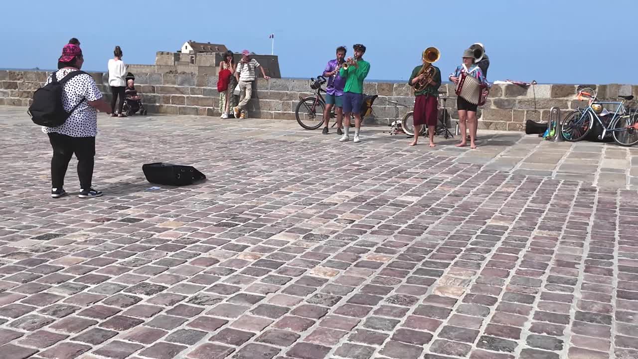 Saint Malo coastal musicians and performers on cobbled street attracting crowds, walking tour Brittany, France