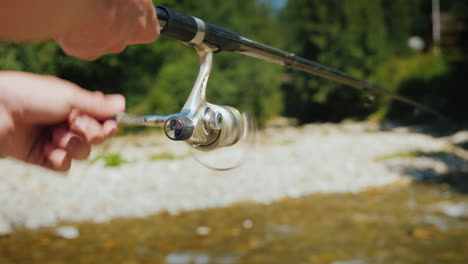 fishing on a small mountain river in the frame of a fisherman's hand with a fishing rod