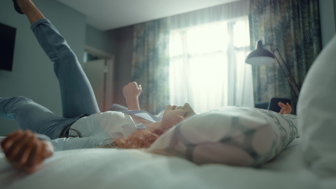 아름다운 커플이 침대에 쓰러지는 호텔 방. 로맨틱한 커플이 신혼여행을 즐기고