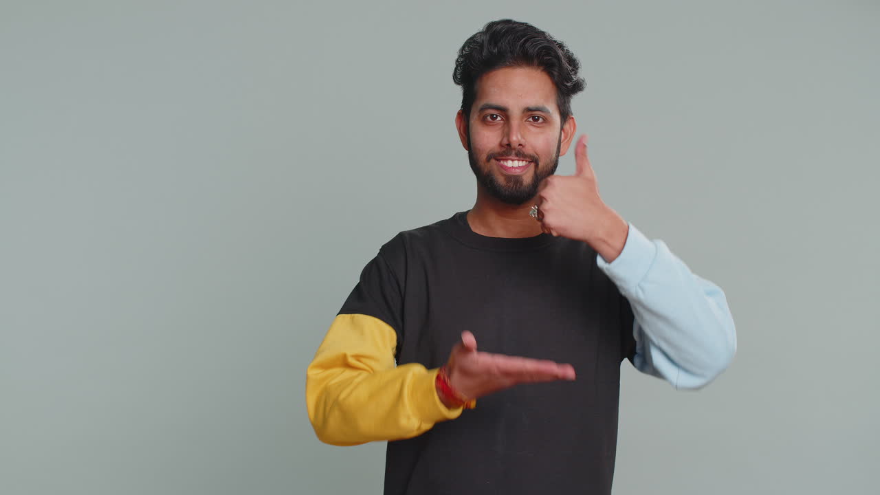 Indian man showing thumbs up pointing empty place advertising area for commercial text copy space
