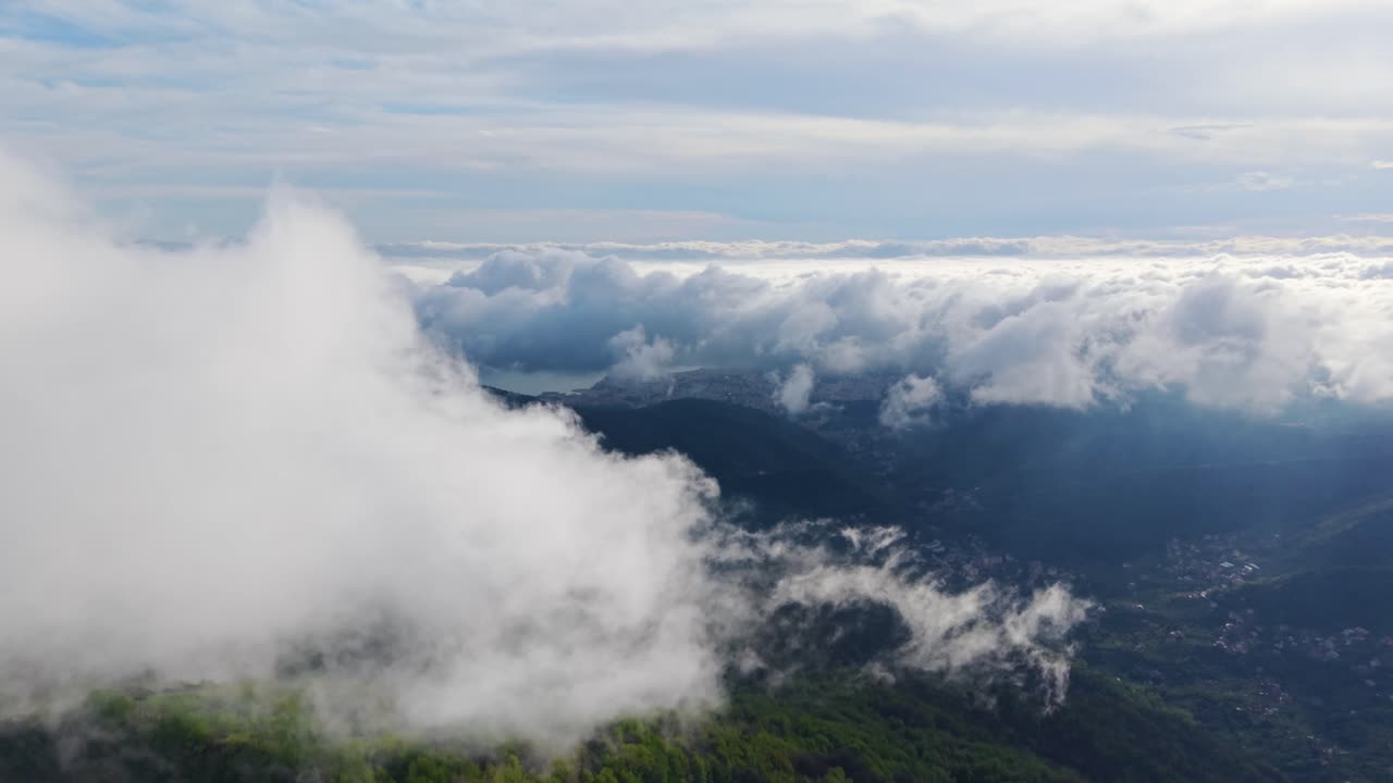 Big clouds floating above green mountain slopes with an aerial view of the landscape