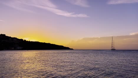 Sailboat-in-calm-waters-during-a-beautiful-sunset-near-a-coast