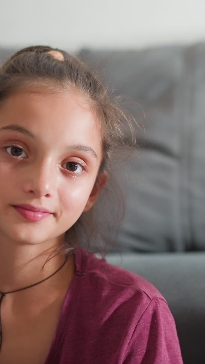 Vista de retrato de un grupo de amigos en el interior mirando directamente a la cámara, con un chico sonriendo alegremente y parpadeando, mientras que la chica mira con calma, creando un ambiente cálido y relajado con una iluminación suave.