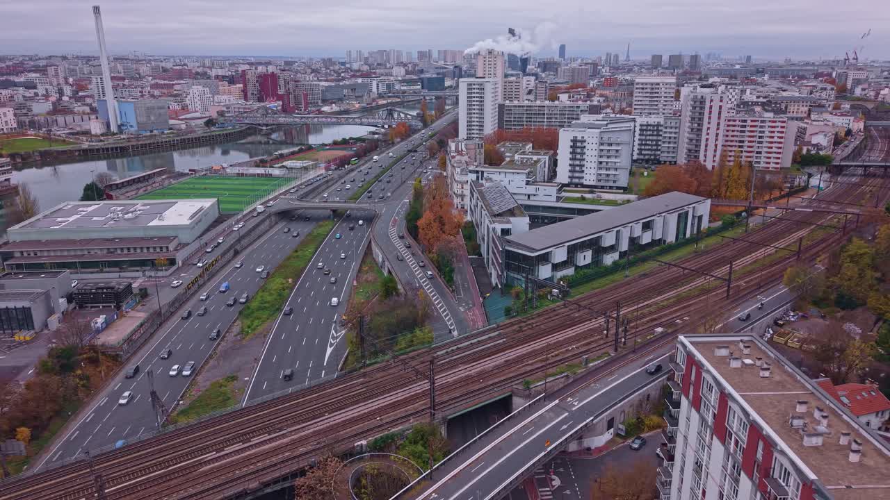 Aerial drone view of highway traffic and railway tracks in Saint-Maurice near Paris. Features the Marne River, Ivry incinerator, and urban skyline in autumn. Ideal for infrastructure concepts, France