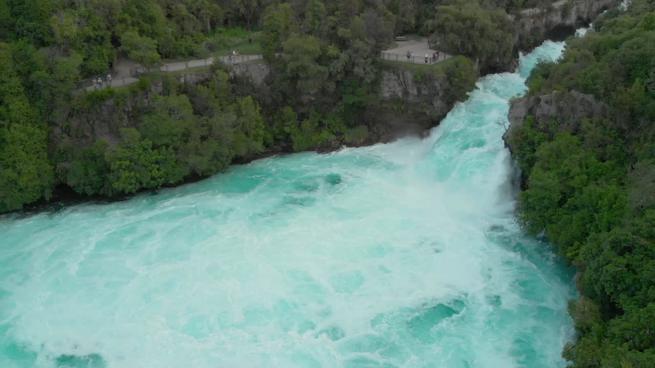 Aerial drone shot of spectacular waterfall Hukas Falls and tourists at viewpoint, New Zealand