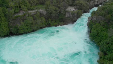 aerial drone shot of spectacular waterfall hukas falls and tourists at viewpoint, new zealand