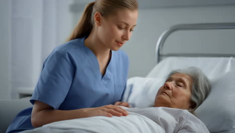 nurse or caregiver providing comfort to an elderly patient in a hospital bed