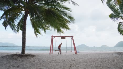 persona sentada en un columpio frente a la playa de bai tam an hai en la isla de con dao, vietnam