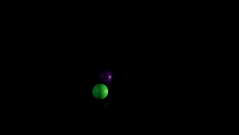 green and purple balls bouncing in darkness