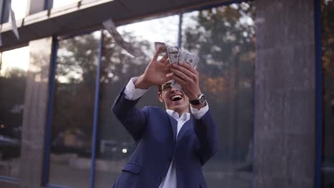 caucasian businessman in blue suit throw handful of banknotes in the air. super excited businessmen in glasses throw cash in