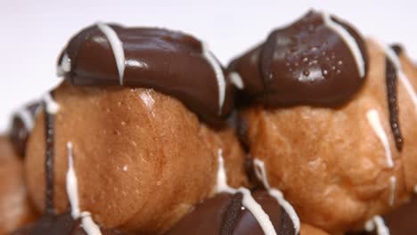 primer plano de deliciosos profiteroles franceses con relleno de crema batida y chocolate en la parte superior