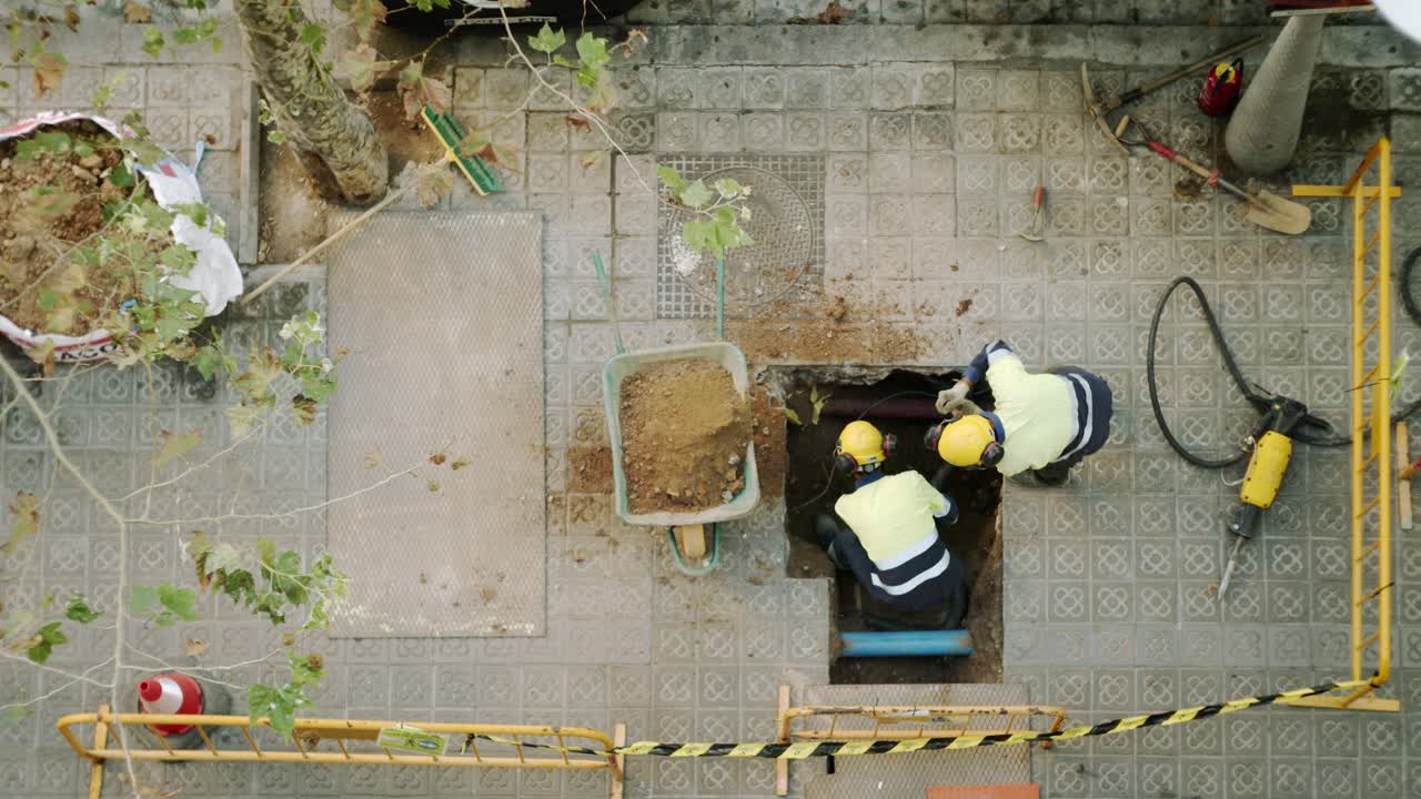 vista superior de los trabajadores de la construcción cavando, paleando y rompiendo un hormigón en una calle de barcelona