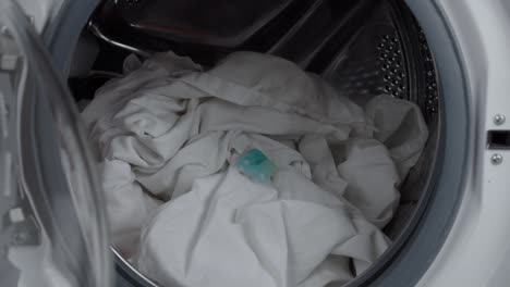 close up static shot of hand putting laundry detergent into washing machine