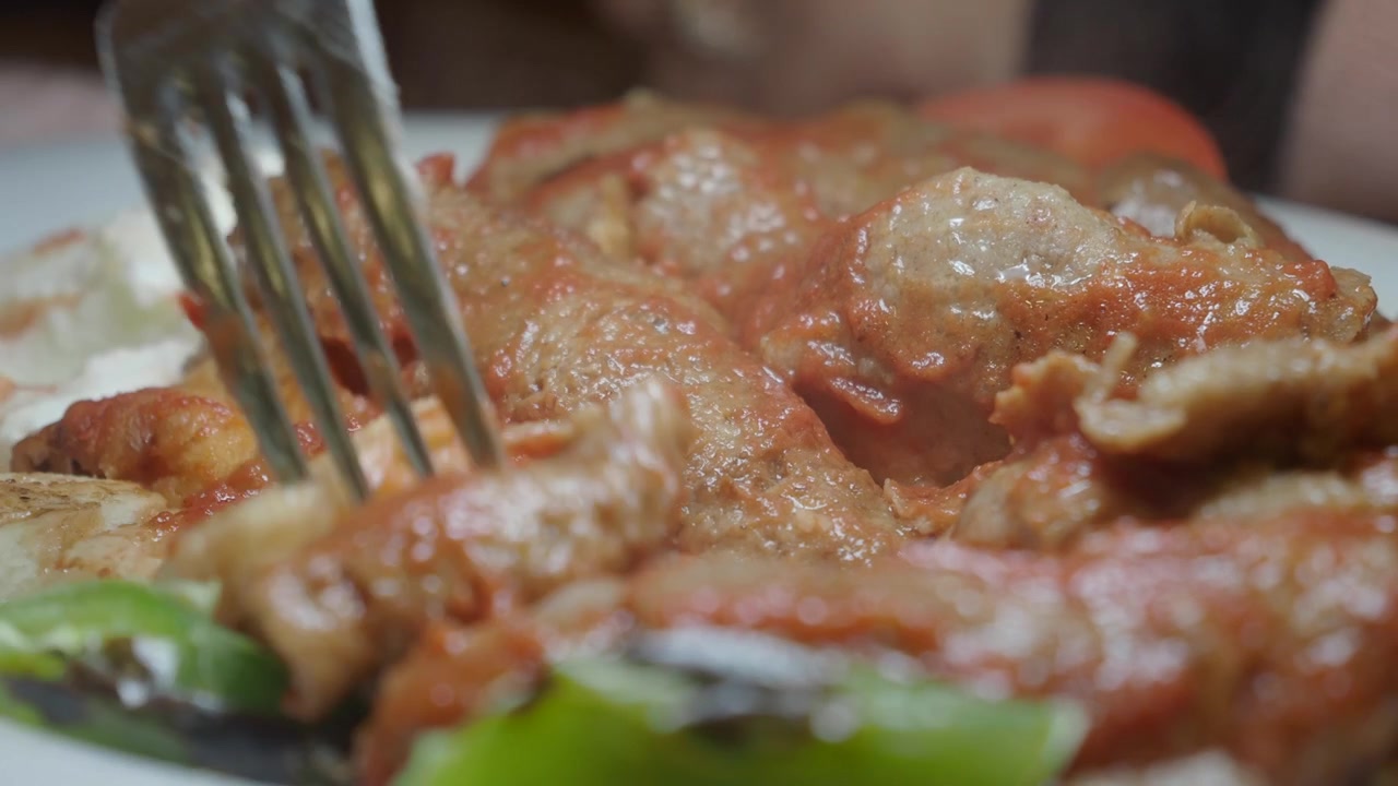 Primo piano di una forchetta che raccoglie un pezzo di Iskender Kebab turco.