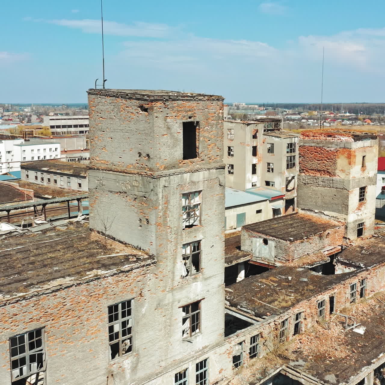 Damaged buildings with broken windows and pitted roof outside. Abandoned place with empty houses after military actions. Aerial view.