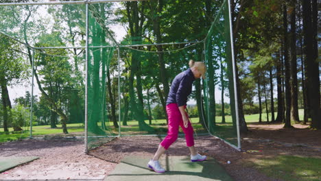 female golf player playing golf and knocking golf ball on net on golf course