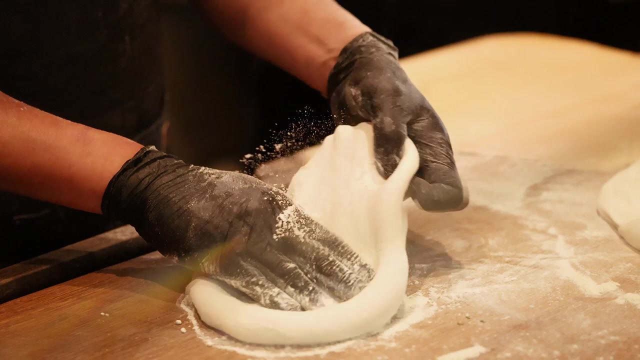 Chef Preparing Pizza Dough on a Floured Wooden Surface