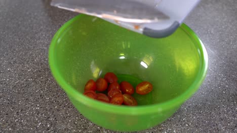 making salad with tomatoes, throwing cherry tomatoes into a green bowl