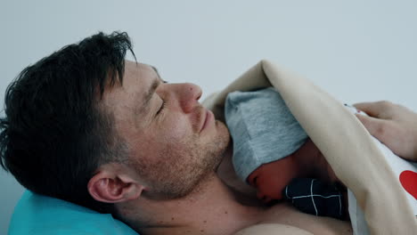caucasian dad is happy to hold his just born child. the baby is put on father's chest for skin to skin contact.