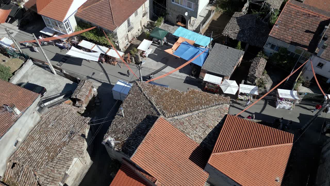 Rotating bird's eye view above street market stands at ethnographic festival pereiro de aguiar lonoa spain