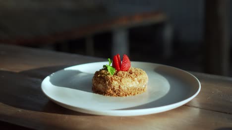 un pequeño pastel de napoleón con fresas en la parte superior de pie en un plato blanco