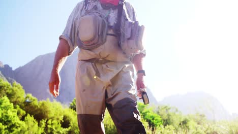 pescador de mosca caminando en el río con caña de pescar