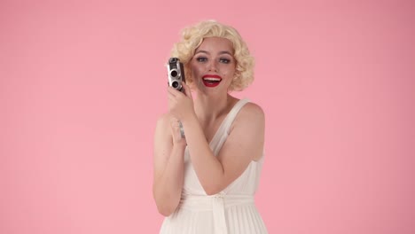 woman in 1940s/50s style dress holding a vintage movie camera