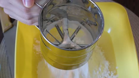 Woman's-hand-sift-flour-through-sieve.-Homemade-bread