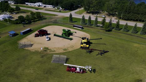 a drone shot of a rural baseball diamond covered in multicolored farm combines tractors and agricultural equipment