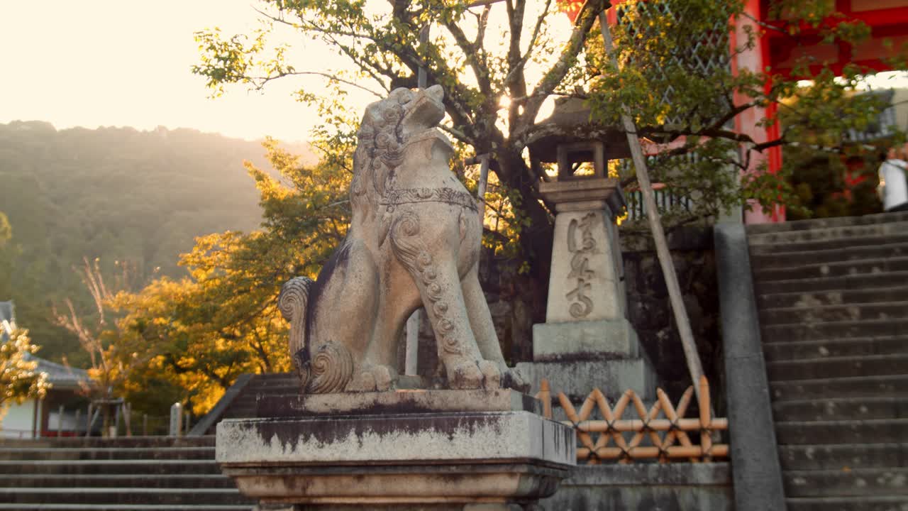 diapositiva de la salida del sol alcanzando su punto máximo a través de los árboles detrás de una hermosa estatua de león en kyoto, japón 4k cámara lenta