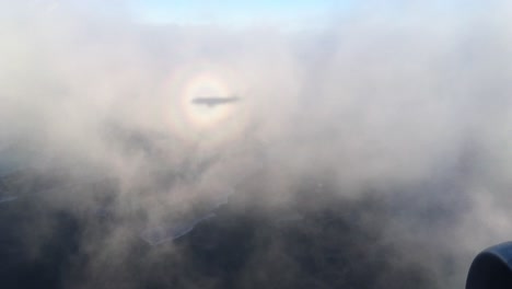 view-from-an-airplane-cast-shadow-on-clouds-while-flying-above-beautiful-islands-and-town