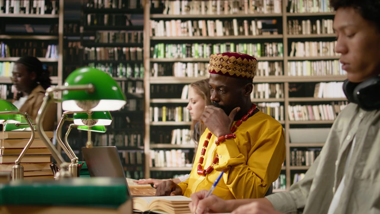 Smiling adult learner working at library table with desktop computer