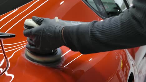 man buffing red car with orbital polisher