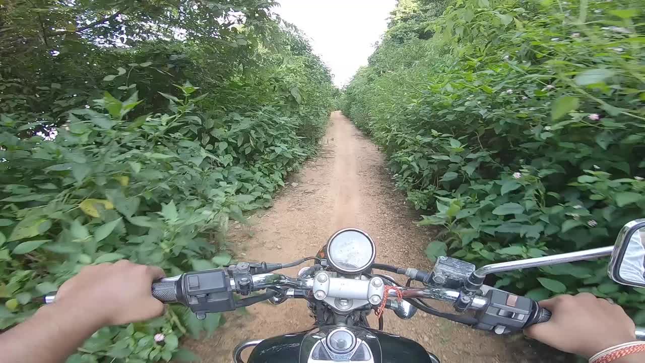 motociclista montando campo a través en un denso callejón verde montando a la montaña en la colina de parasnath en jharkhand, india