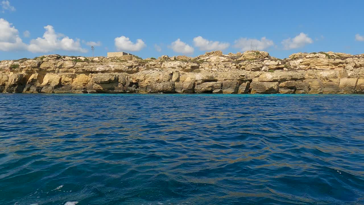 Low-angle sea-level view from sailing boat of Favignana island and turquoise sea water in Sicily, Italy