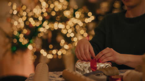 hombre atando cinta a la caja de regalos en casa
