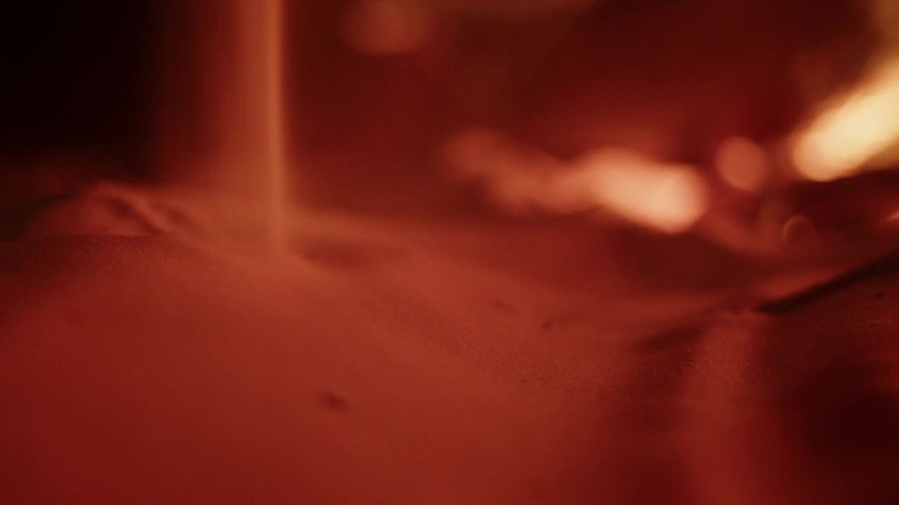 Primo piano di sabbia fine del deserto che cade in un flusso continuo di notte in Tunisia. Scatto macro suggestivo con illuminazione calda, che si concentra su texture, flusso e il concetto del tempo che passa.