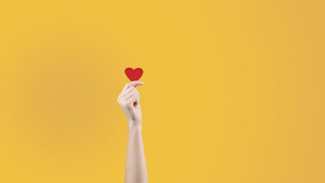 female blogger hold in hand little red heart on yellow orange background. like in social network. valentines day, international women day, love