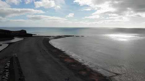 Luftaufnahme-Vom-Abstieg-über-Budleigh-Salterton-Beach,-Devon,-England,-Mit-Der-Sonne,-Die-Auf-Dem-Ruhigen-Meer-Glitzert