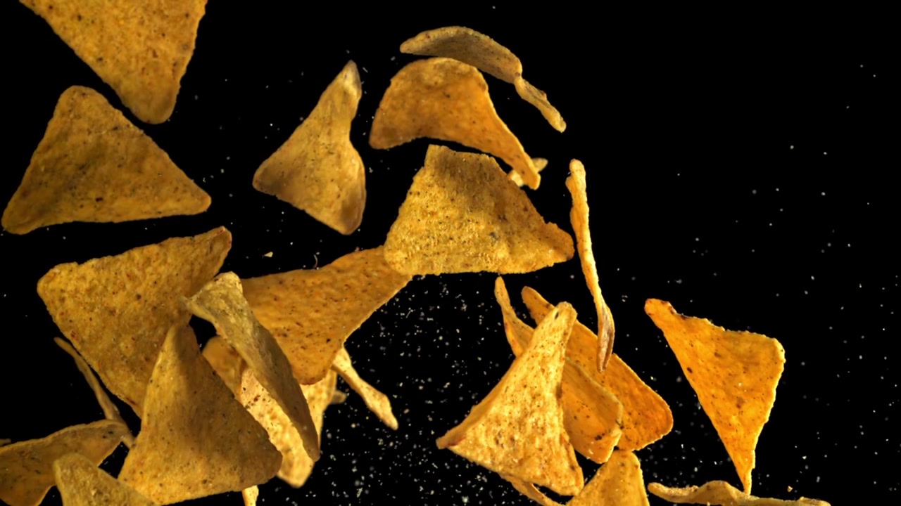 Slow motion av tortillachips som flyger och faller på svart bakgrund