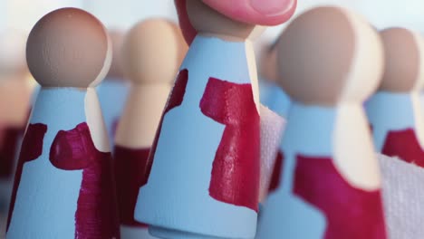 Red-And-Blue-Painted-Peg-Dolls-Being-Placed-In-Rows,-Close-Up-Shot