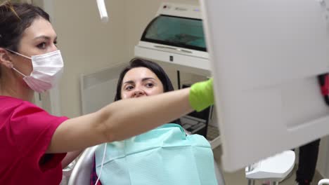 young female dentist examining the mouth of a patient with an intraoral camera and showing image on the screen explaining to the patient the result of the examination. shot in 4k