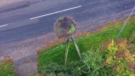 empty stork nest on electricity pole near road, aerial orbit view